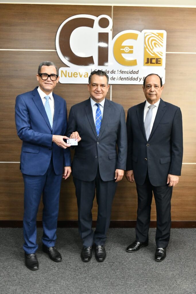 El.ministro de Trabajo,  Eddy Olivares Ortega, recibe la cédula de magistrados Roman Jaquez Liranzo y Rafael Vallejo Santelises, presidente y miembro titular de la JCE, respectivamente.